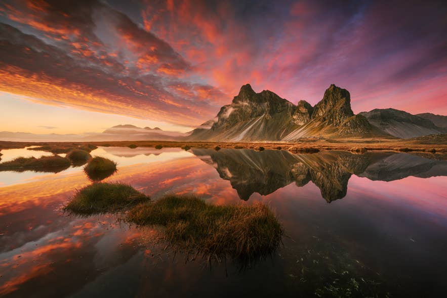 Sunset over Vestrahorn mountain in Iceland, with colorful skies reflected in calm water. Sunset over Vestrahorn mountain in Iceland, with colorful skies reflected in calm water.