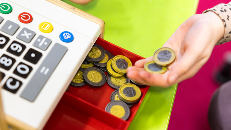 Photo shows a child playing with a toy cash register.