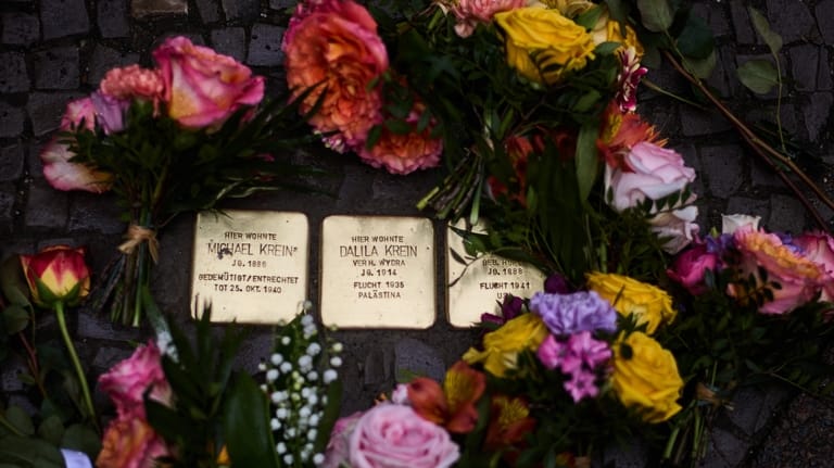 Flowers lay near palm-sized brass Holocaust plaques of the Krein...