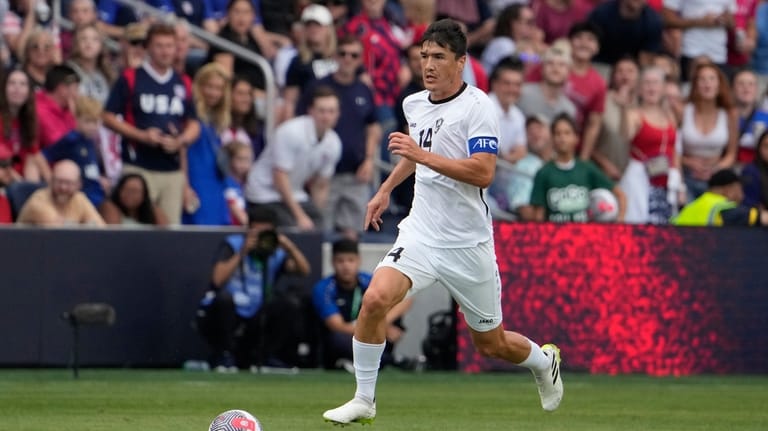 Uzbekistan's Eldor Shomurodov (14) brings the ball down the pitch...