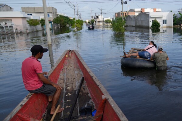 Residents wade through a flooded neighborhood in Monteria, Colombia, Feb. 10, 2026. (AP Photo/Fernando Vergara, File)