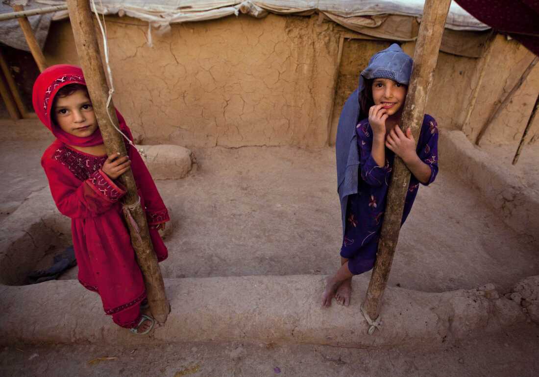 FILE: Zareena, left, and Shakeela, internally displaced Afghan girls play outside a shanty at a refugee camp in the outskirts of Kabul, Afghanistan, Monday, July 25, 2011.