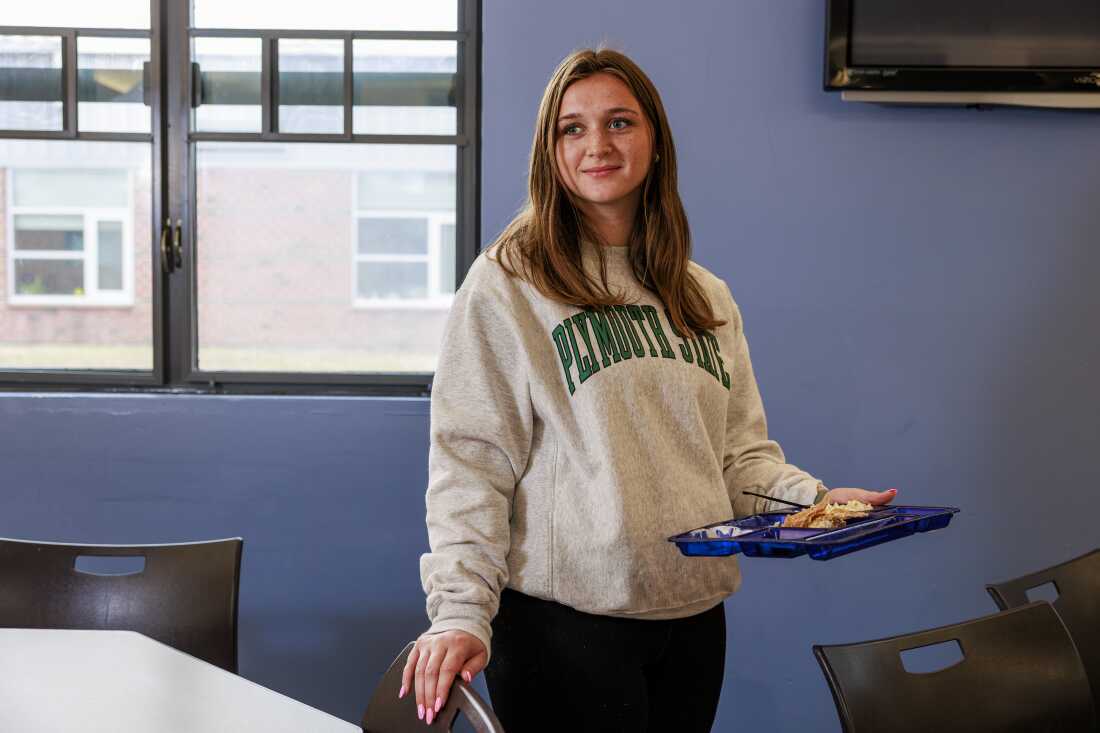 Mady Worcester stands at school, holding a cafeteria plate of fish tacos in one hand.