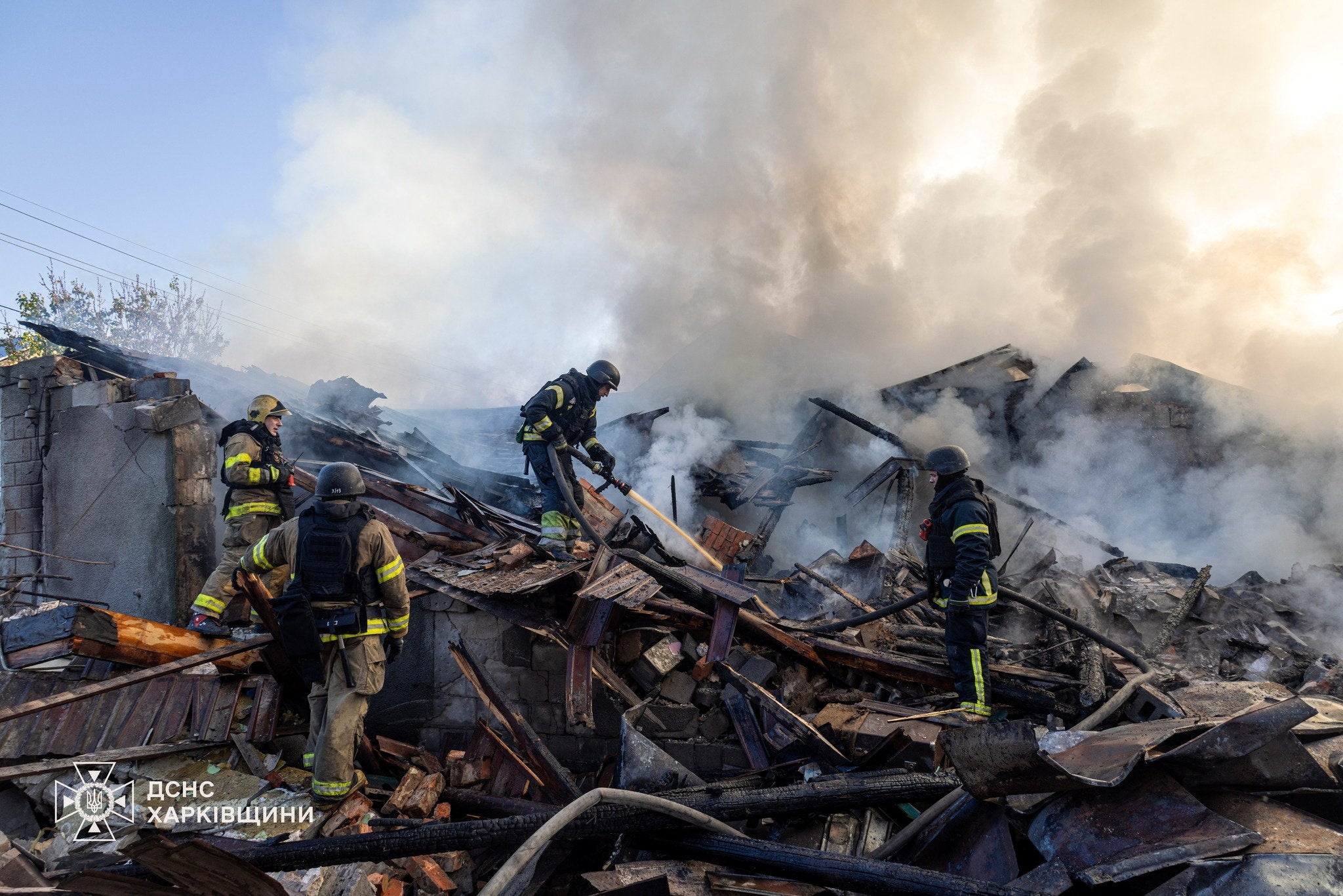 Firefighters work at the site of a private household hit during morning Russian drone strikes in Kharkiv