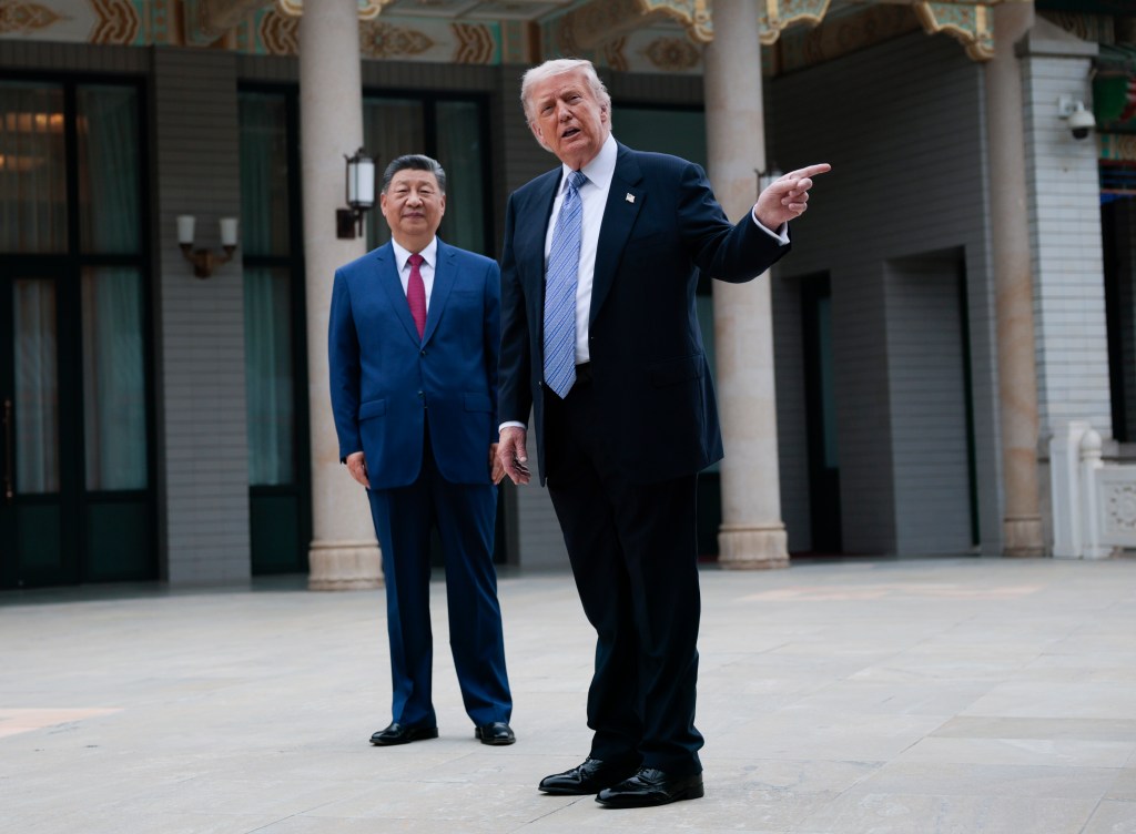 Donald Trump gestures with his right hand as Chinese President Xi Jinping stands beside him.