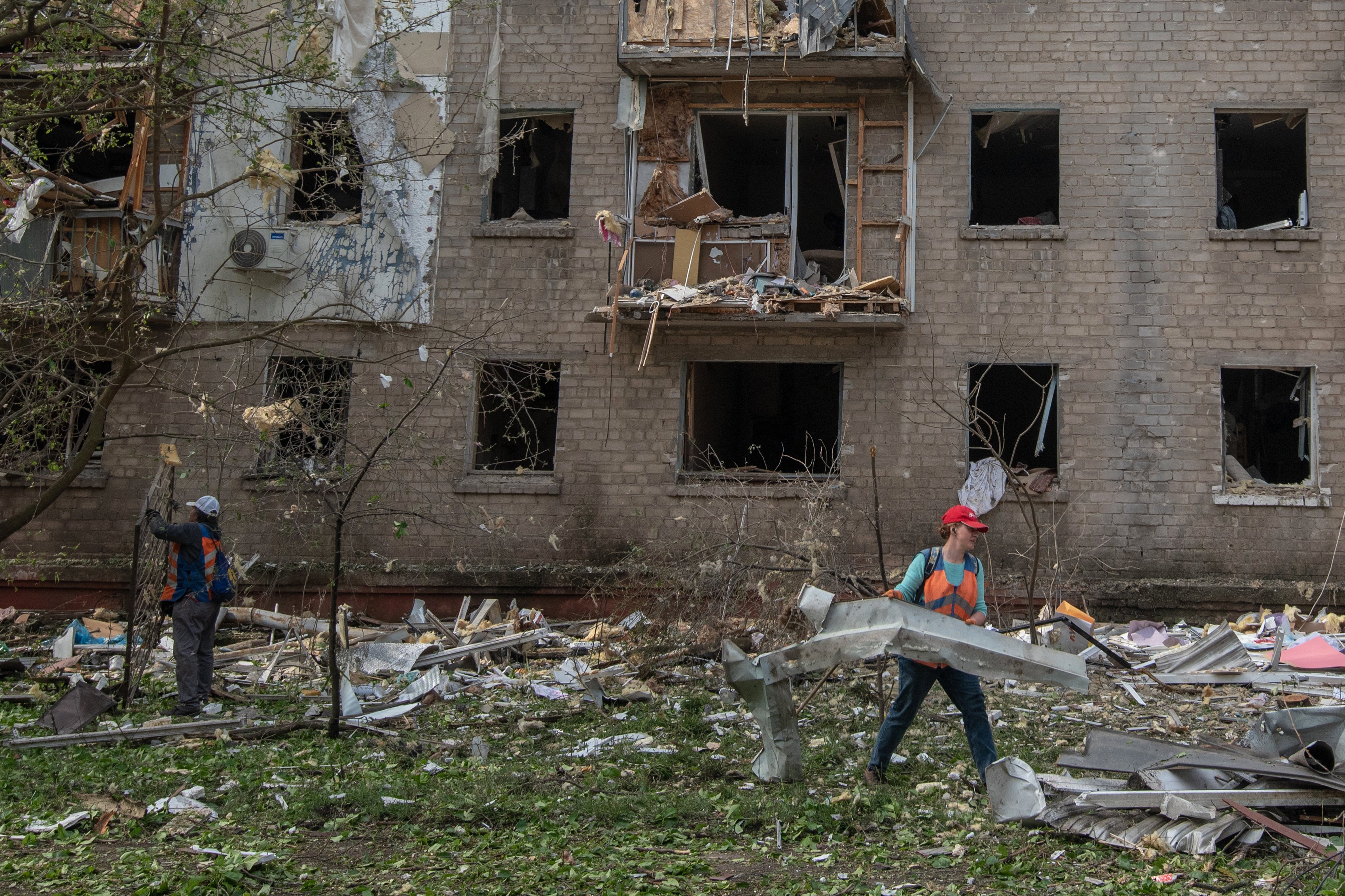 Workers clear debris in the courtyard of a damaged residential building following an air attack in Dnipro on 18 May