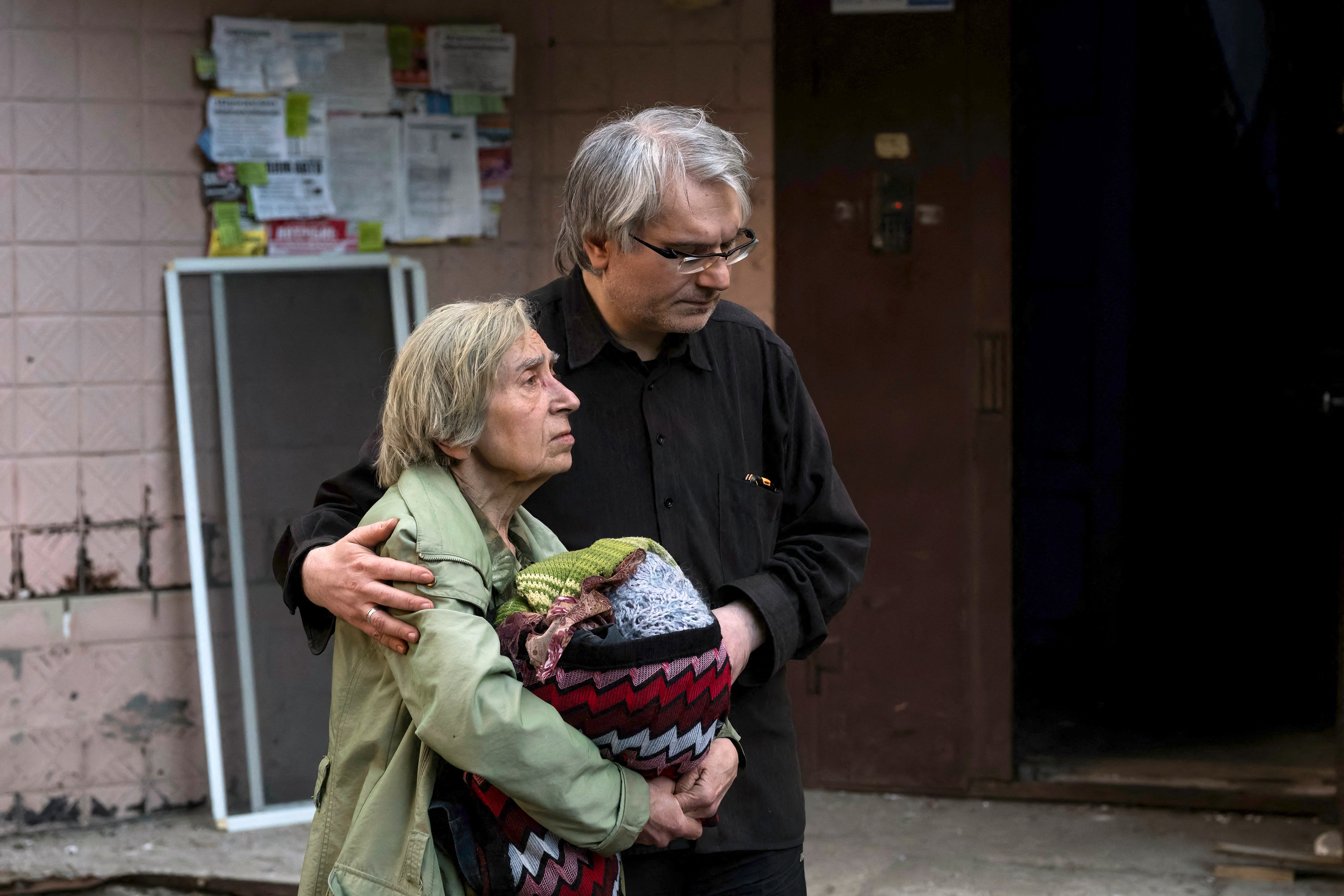 A man escorts a local resident during the evacuation of a damaged residential building following Russian strikes to the Ukrainian capital in Kyiv