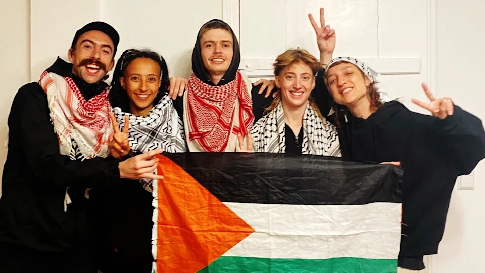 Activists of the Ulm 5 - holding a Palestinian flag and showing peace signs - They include Daniel Tatlow-Devally (Ireland), Zo Hailu (UK), Crow Tricks (UK), Vi Kovarbasic (Germany), Leandra Rollo (Spain)
