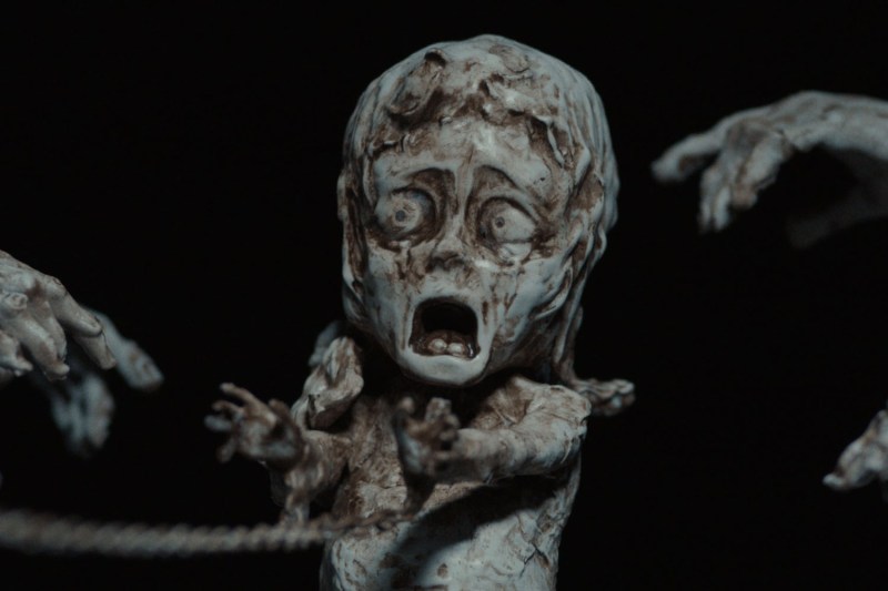A miniature sculpture of a girl who has her hands tied and appears in distress.