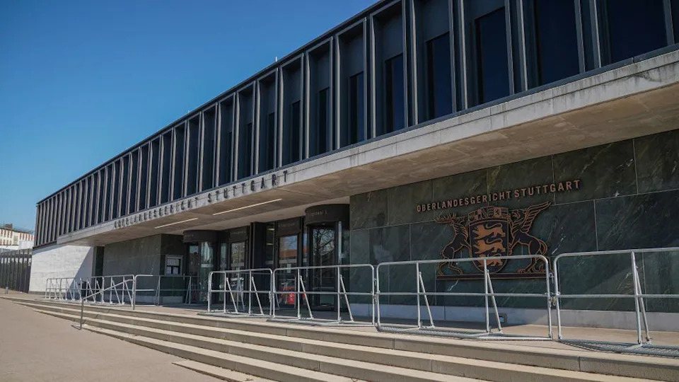 A brutalist building with green and grey stone walls with a gold emblem on the side reading Oerlandesgericht Stuttgart