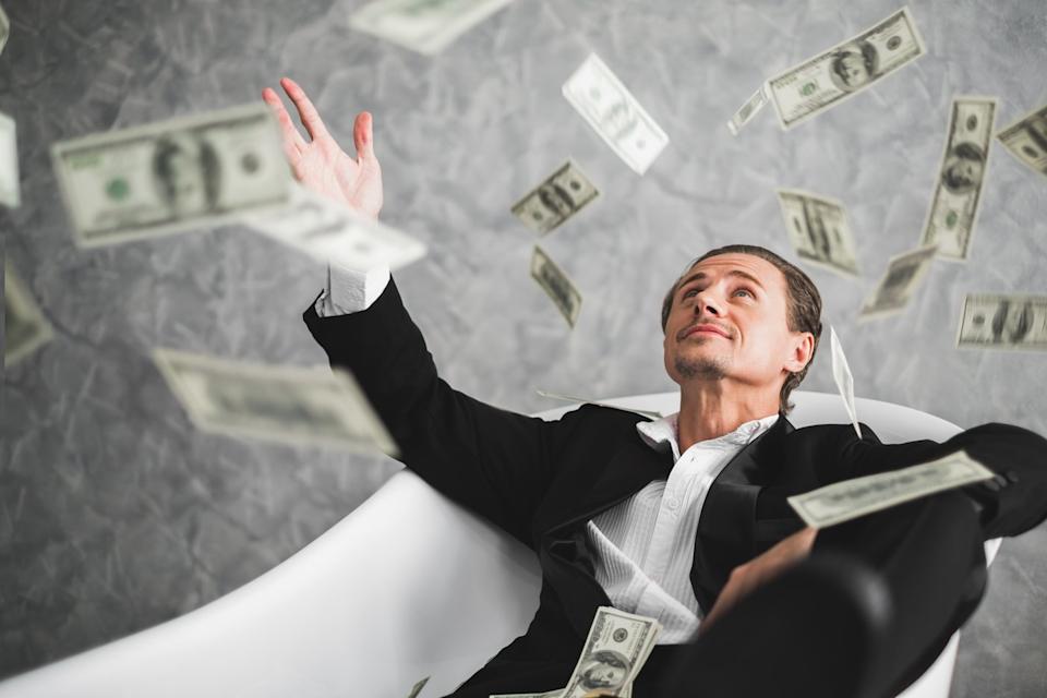 Investor throwing money into the air.