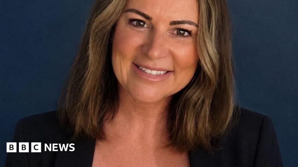 Restore Britain announces Makerfield by-election candidate Restore Britain candidate, Rebecca Shepherd. She has shoulder-length dark hair, is wearing a dark blazer and a white blouse.
