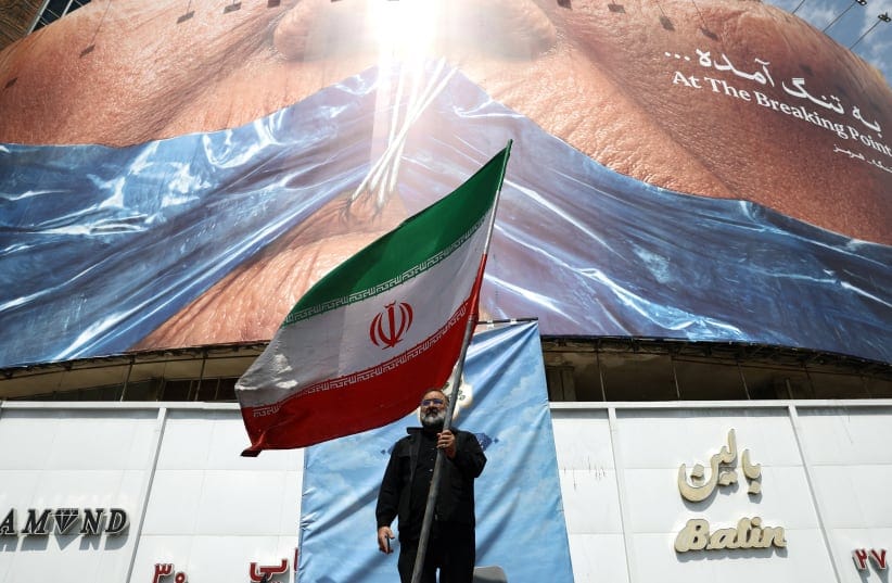 A man holds an Iranian flag near an anti-US billboard depicting US President Donald Trump and the Strait of Hormuz, in Tehran, Iran, May 2, 2026. 