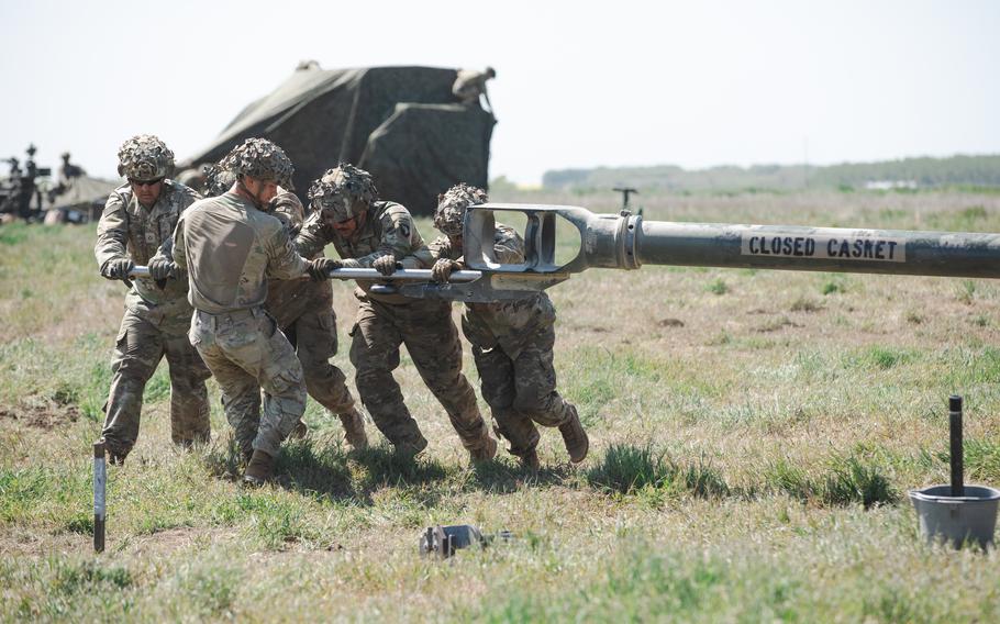 A group of troops in move part of a Howitzer.