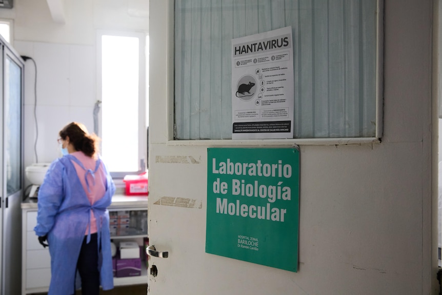 A woman in scrubs stands in a room in a hospital.