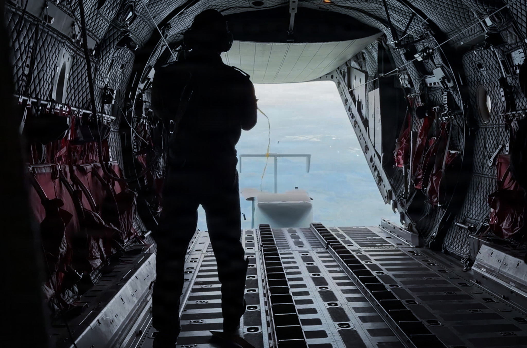 An airman with the Romanian air force observes a Long Range Grasshopper system following deployment from an Alenia C-27J Spartan aircraft during Exercise Trojan Footprint 26 near Cincu, Romania, May 15, 2026. The demonstration highlighted interoperability between NATO Allies while supporting long-range precision sustainment capabilities. (U.S. Army National Guard photo by Staff Sgt. Melyssa Vazquez)