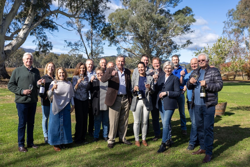 A group of people stand together holding glasses of wine