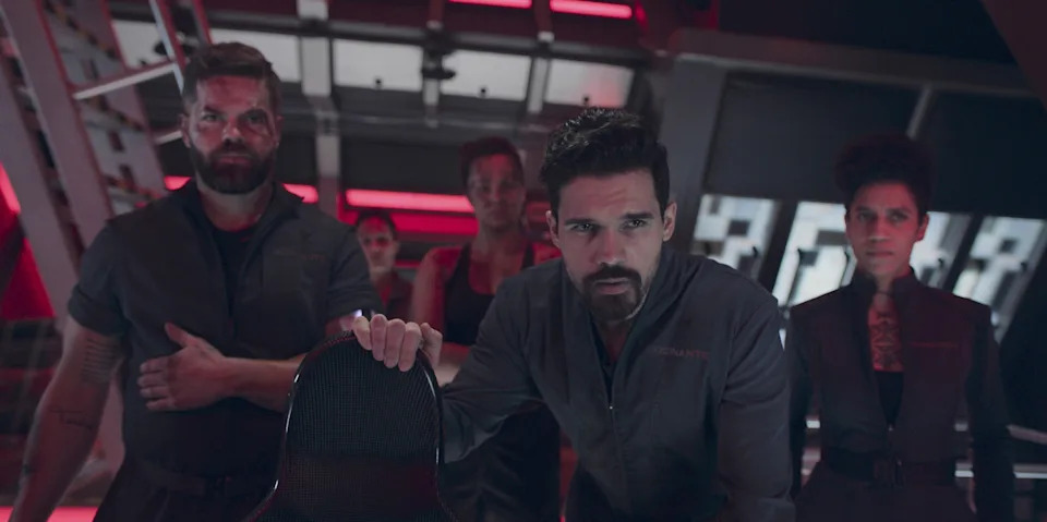 Group of actors in futuristic outfits on a spaceship set, looking intense and focused