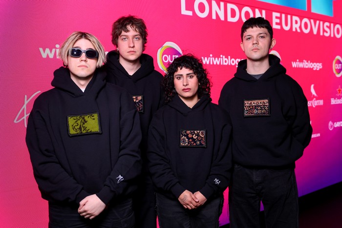 Four people stood in a row wearing matching black hoodies with their hands crossed.