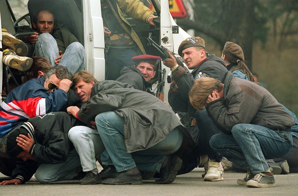 TOPSHOT - A Bosnian special forces soldier returns fire 06 April 1992 downtown Sarajevo as he and civilians come under fire from Serbian snipers. The Serb extremists were shooting from the roof of a hotel at a peace demonstration of some of 30,000 people as fighting between Bosnian and Serb fighters escalated in the capital of Bosnia-Hercegovina. 