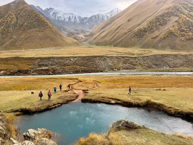 Sweeping mountains with people hiking around a little lake in the foreground