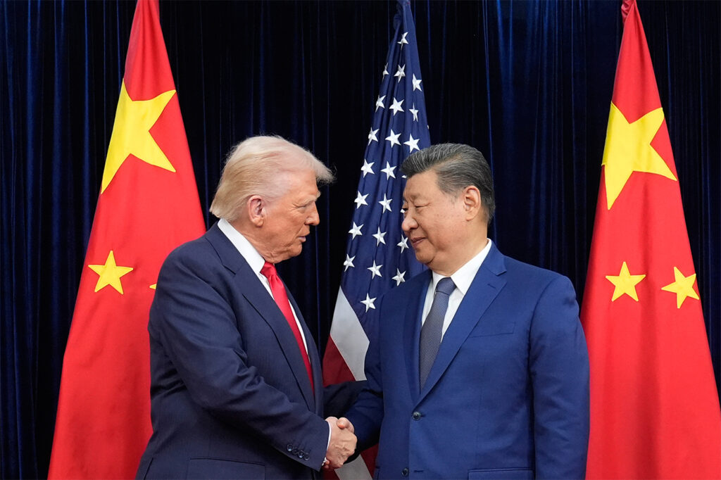 President Donald Trump and Chinese President Xi Jinping shake hands between both nations' flags.