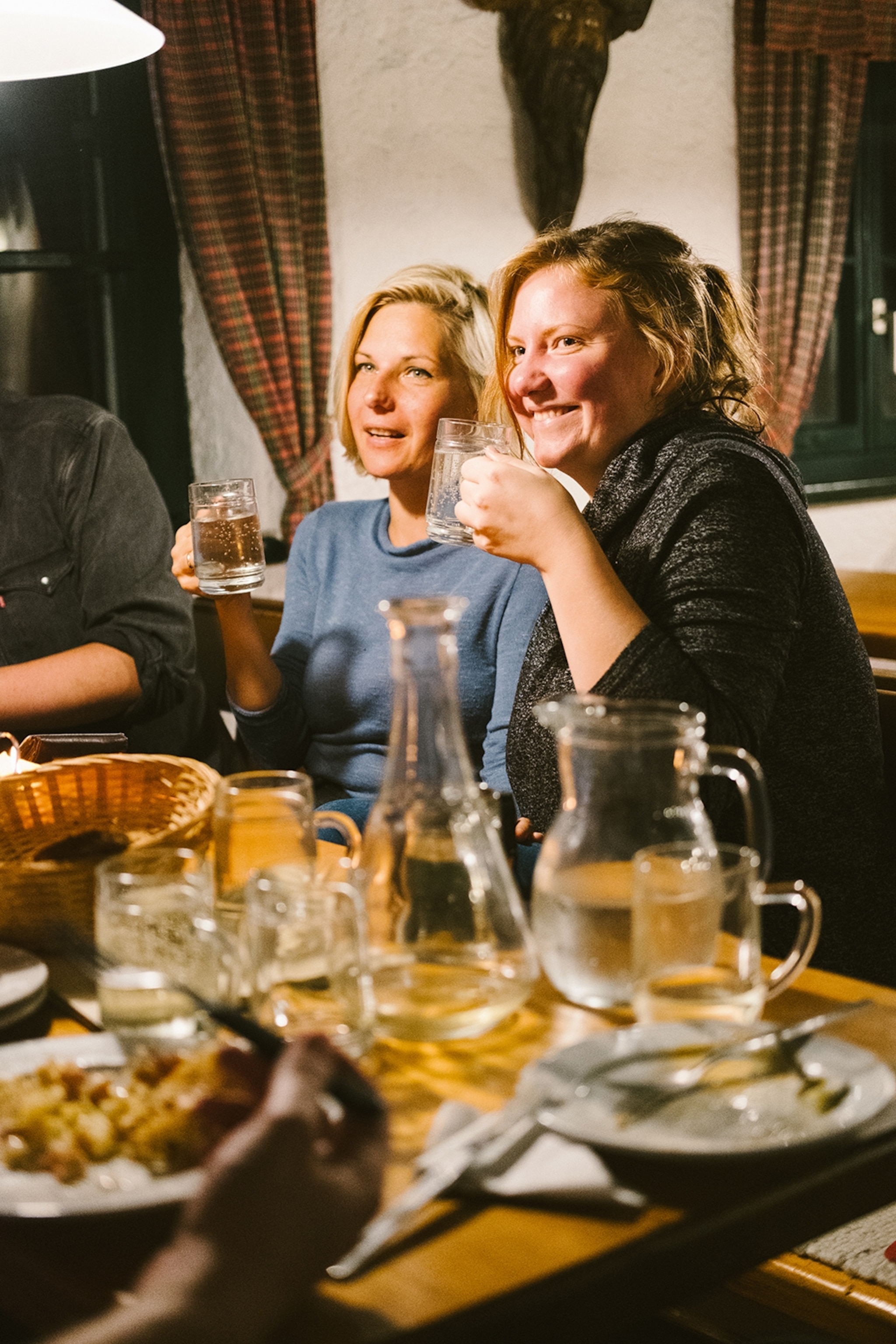 A couple of female friends in a traditional, cosy Viennese pub, drinking wine spritzers.