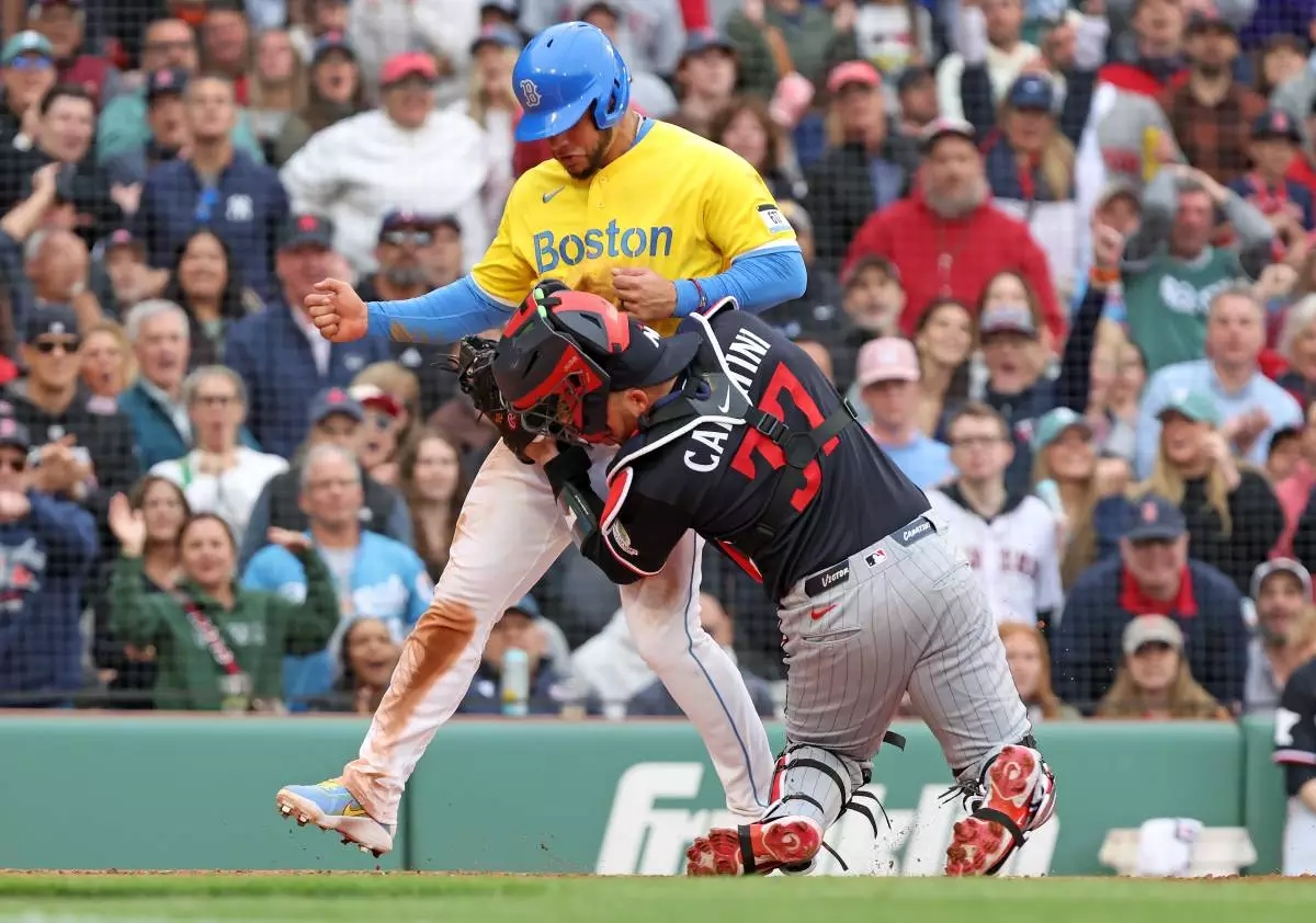 Boston Red Sox' Willson Contreras is tagged out by Minnesota Twins catcher Victor Caratini as he tries to score in the fourth inning of a baseball game, Saturday May 23, 2026 in Boston. (AP Photo/Jim Davis)