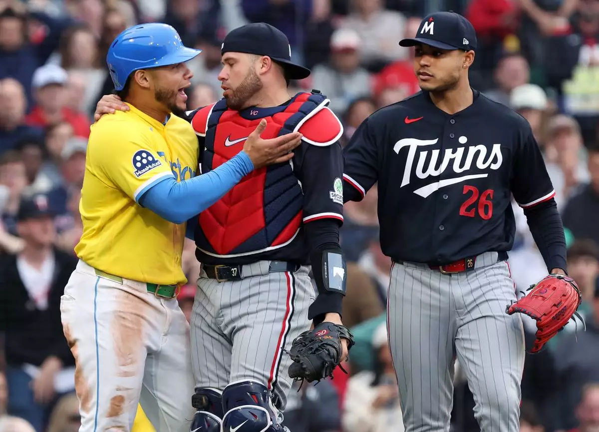 Boston Red Sox's Willson Contreras, left, and Minnesota Twins catcher Victor Caratini, center, exchange words as Twins pitcher Taj Bradley, right, looks on after a play at the plate during the fourth inning of a baseball game, Saturday May 23, 2026, in Boston. (AP Photo/Jim Davis)