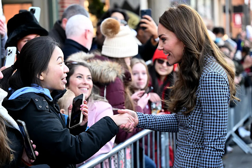 The Princess of Wales shaking hands with a woman standing behind a barricade.