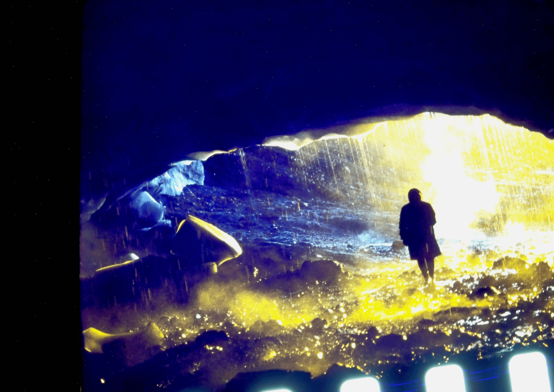 A silhouetted person stands beneath the vaulted ceiling of a glacial cave in Iceland. Image: Archival Materials Courtesy of Andri Snær Magnason.
