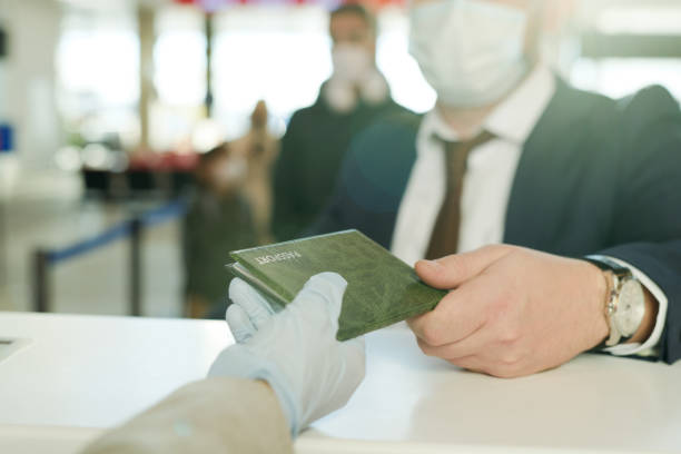 Traveler wearing a face mask hands over a passport at an airport check-in counter