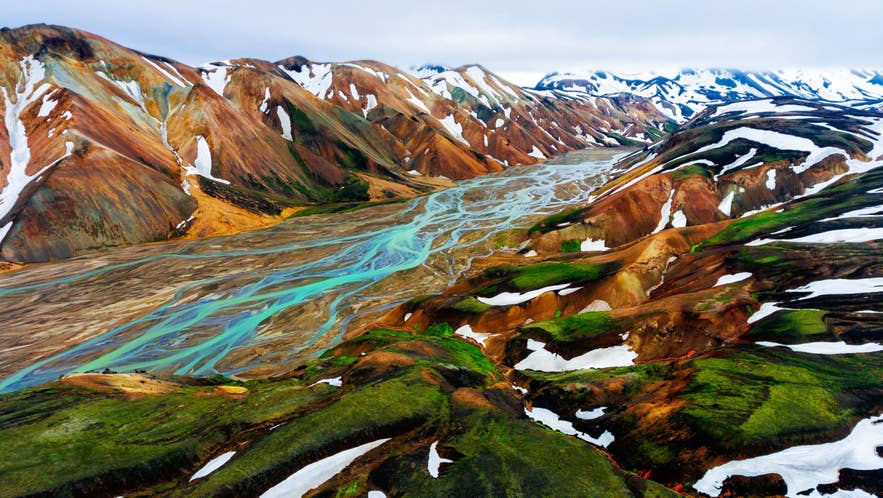 Aerial view of Landmannalaugar rhyolite mountains and turquoise braided river in Iceland Highlands.