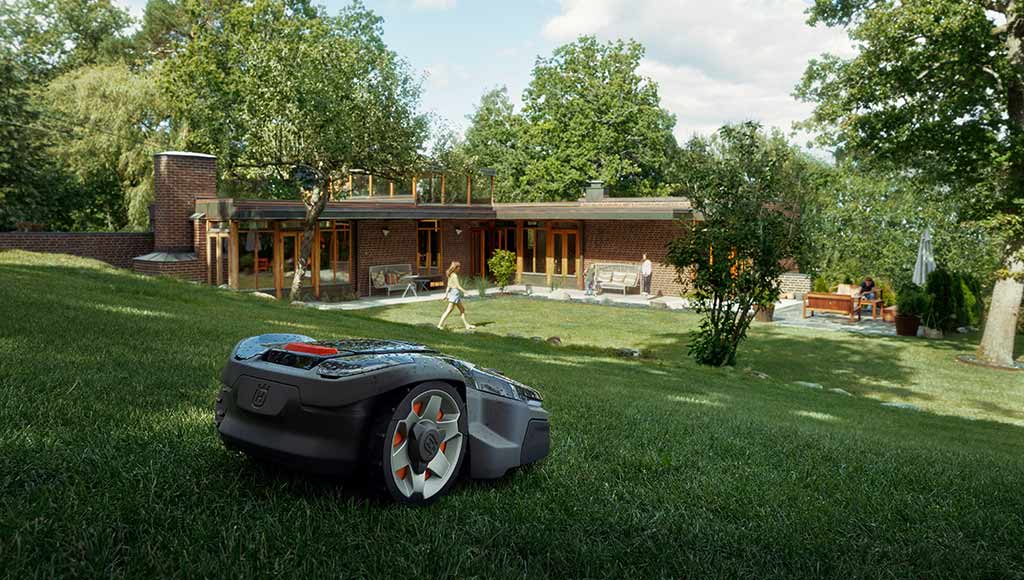 A Husqvarna lawnmower on a large green space in front of a house