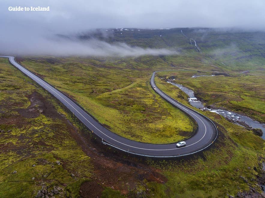 Car driving on a winding Ring Road stretch in misty mountains, a classic road trip scene in Iceland in April. Car driving on a winding Ring Road stretch in misty mountains, a classic road trip scene in Iceland in April.
