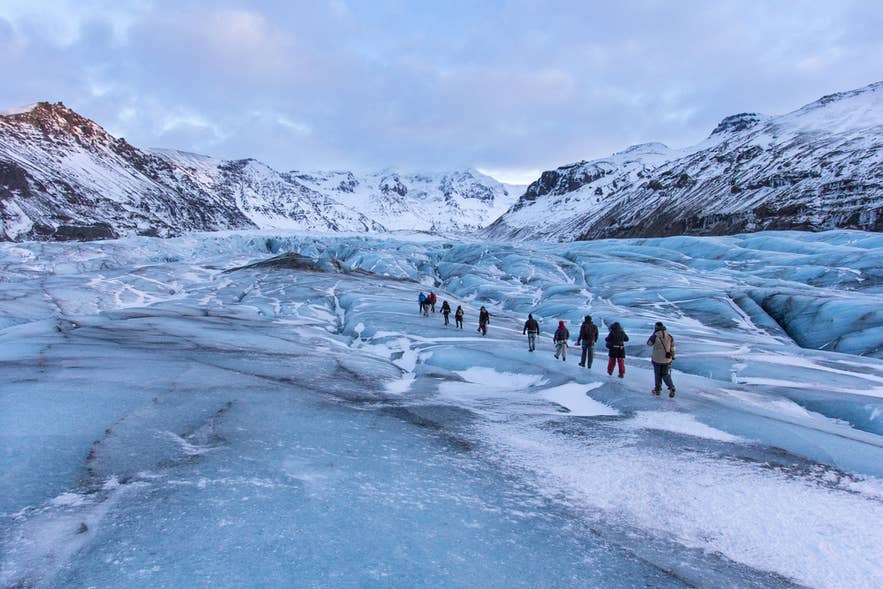 Group hiking on the Solheimajokull Glacier in Southern Iceland in April with blue ice and snowy peaks. Group hiking on the Solheimajokull Glacier in Southern Iceland in April with blue ice and snowy peaks.