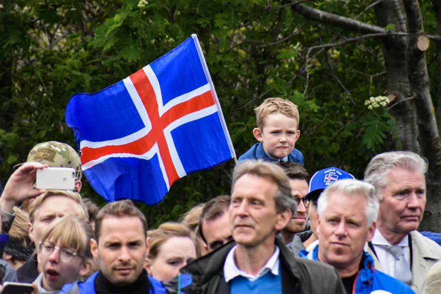 An Icelandic flag stands in the middle of a group of people An Icelandic flag stands in the middle of a group of people