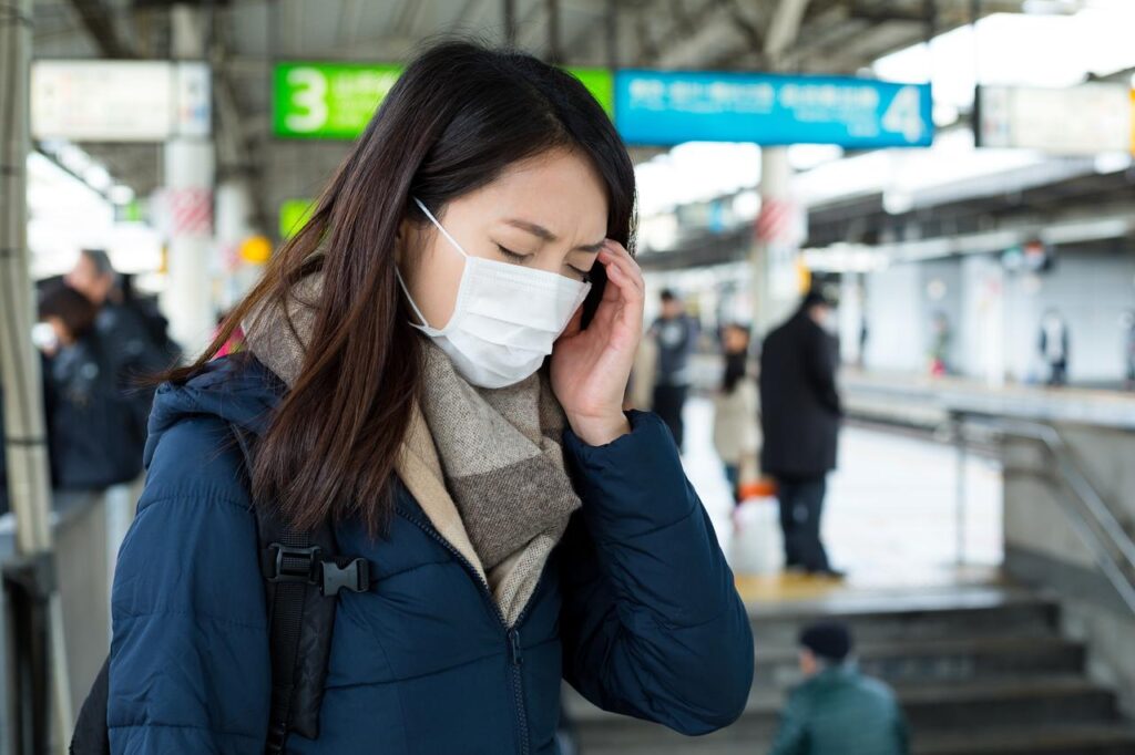 A woman wearing a face mask appears to suffer from hay fever symptoms at a train station in Japan. (Adobe Stock Photo)