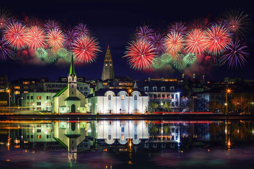 Fireworks over Reykjavik with Hallgrimskirkja and Tjörnin pond reflections during New Year’s Eve in Iceland