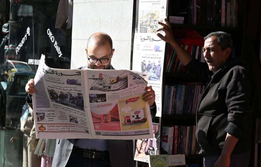 A man reads the Syrian state-run newspaper Al-Thawra on a street in Damascus. The paper is the first official print newspaper to be published in its new format following the fall of the Assad regime, December 1, 2025. (AFP)