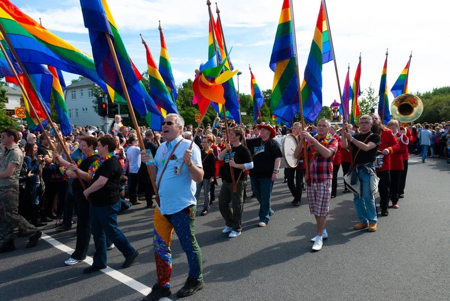 Reykjavik Pride parade in Iceland with people marching, rainbow flags waving, and a band playing in celebration. Reykjavik Pride parade in Iceland with people marching, rainbow flags waving, and a band playing in celebration.