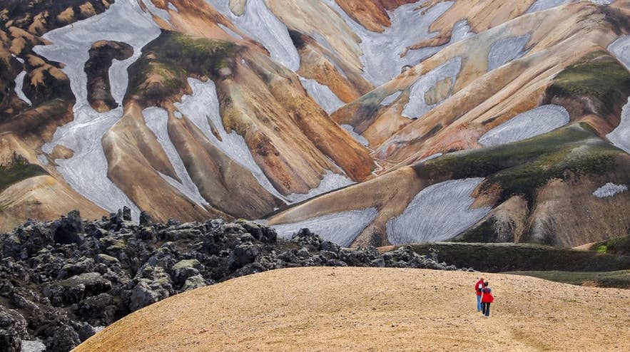 Hikers explore colorful rhyolite mountains in Landmannalaugar, with trails often mapped on an Iceland app like AllTrails.