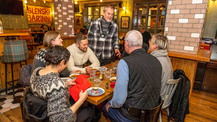 Group enjoying Icelandic cuisine and conversation inside a cozy local restaurant in Reykjavik.
