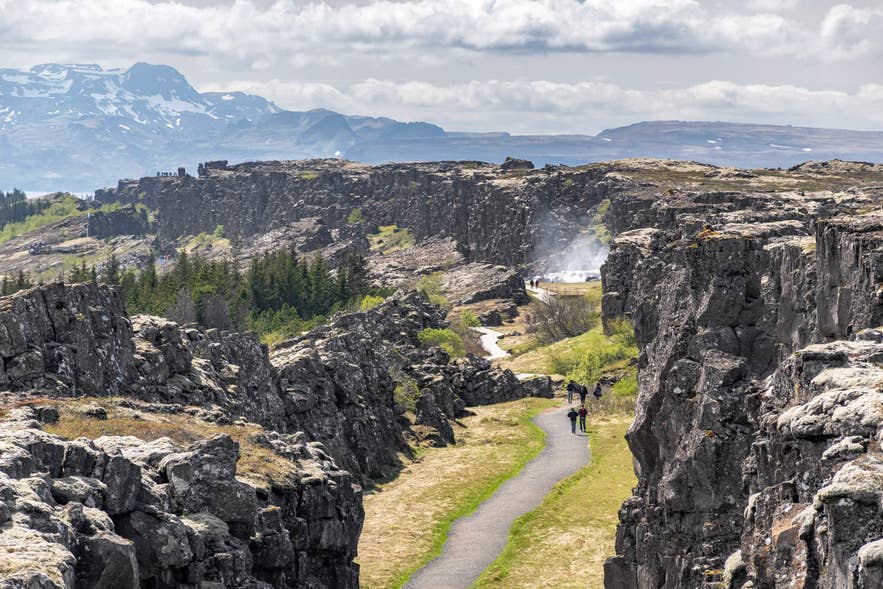 Scenic hiking path through a rocky gorge and distant mountains in Thingvellir National Park.