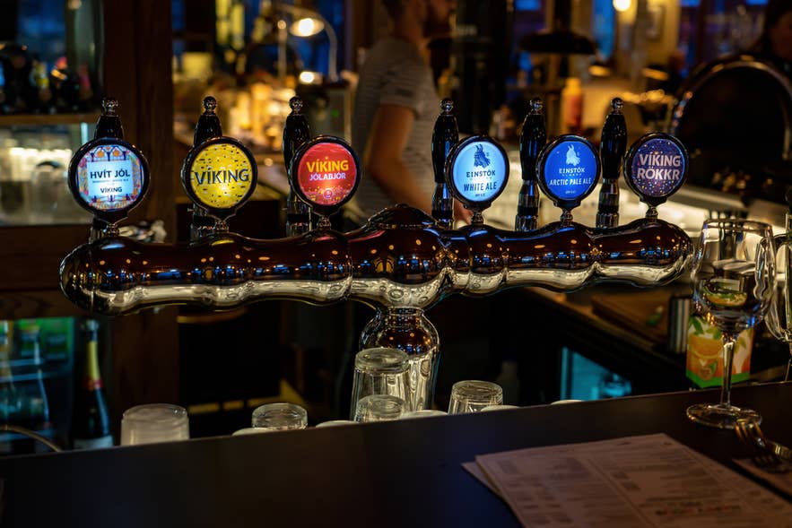 Icelandic draft beer taps at a Reykjavik bar showcasing Viking and Einstok brews on polished chrome tower.