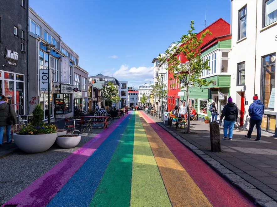 Pedestrian rainbow street with colorful shops and people walking in Reykjavik.