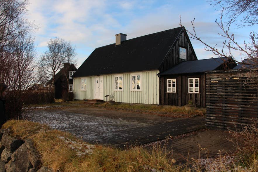 A black-and-white wooden house stands quietly in a frosty yard with bare trees and a cloudy blue sky overhead. A black-and-white wooden house stands quietly in a frosty yard with bare trees and a cloudy blue sky overhead.