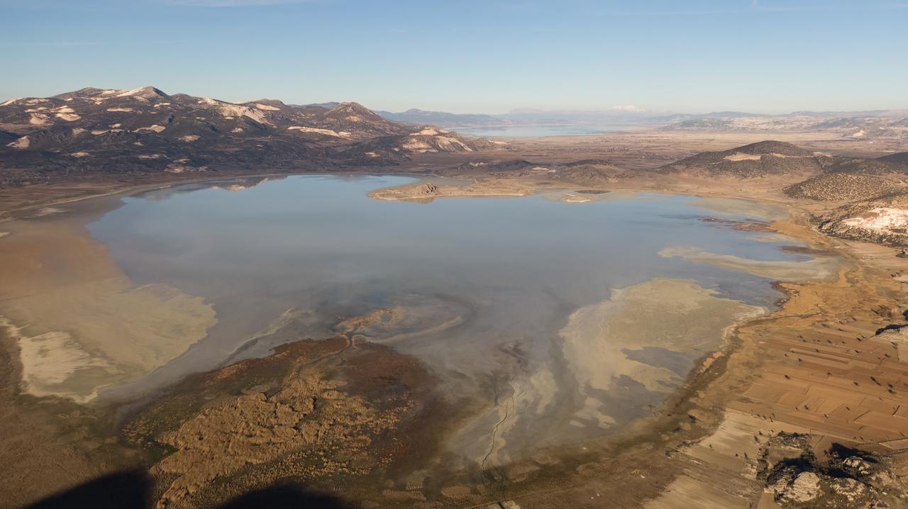 Aerial view of lake water and cracking soils due to drought. Mountain landscape destroyed by marble quarries Lake Yarışlı, Türkiye (Adobe Stock Photo)