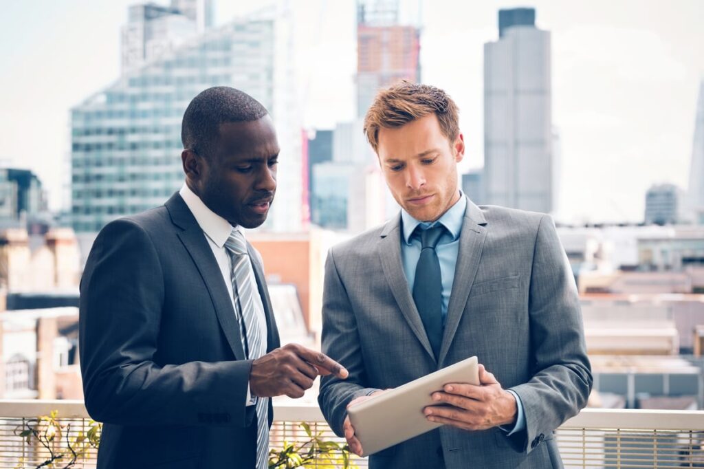 Better Artificial Intelligence (AI) Stock: Alphabet or Microsoft Two investors looking at a tablet.