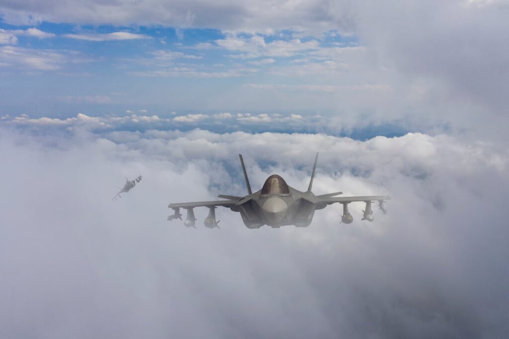 This AI Stock Keeps Winning Contracts Its Competitors Can’t Even Bid On A fighter jet flies above the clouds.